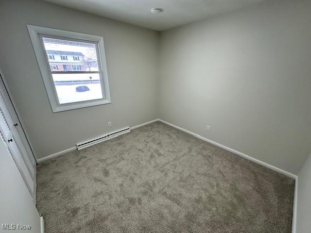 unfurnished room with light colored carpet and baseboard heating