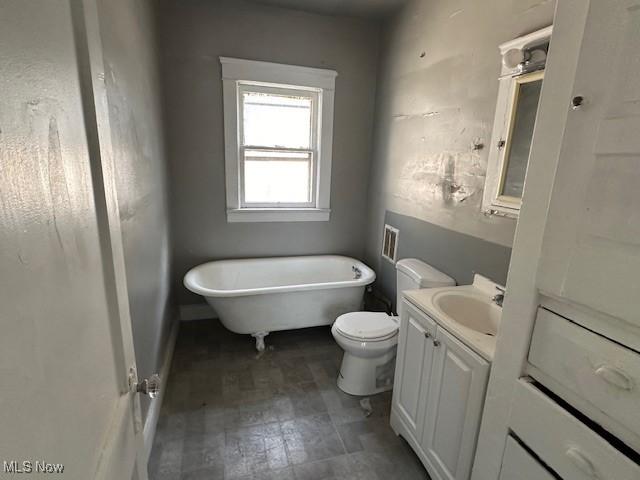 bathroom with a tub to relax in, vanity, and toilet