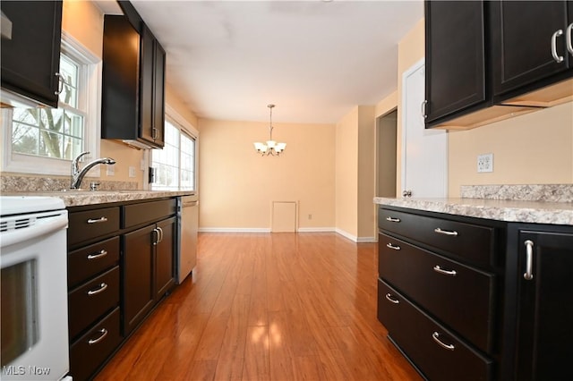 kitchen with an inviting chandelier, electric stove, light wood-type flooring, hanging light fixtures, and sink