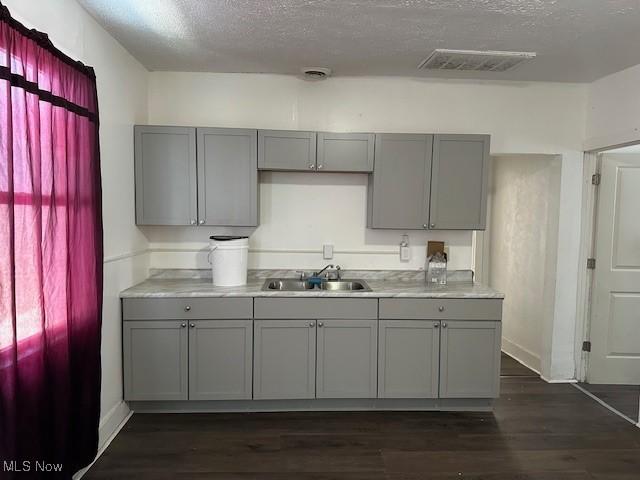 kitchen featuring dark wood-type flooring, sink, gray cabinetry, and a textured ceiling