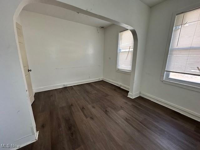 spare room featuring dark wood-type flooring and plenty of natural light