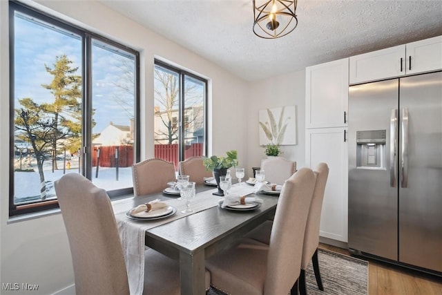 dining area featuring light wood-type flooring and a textured ceiling