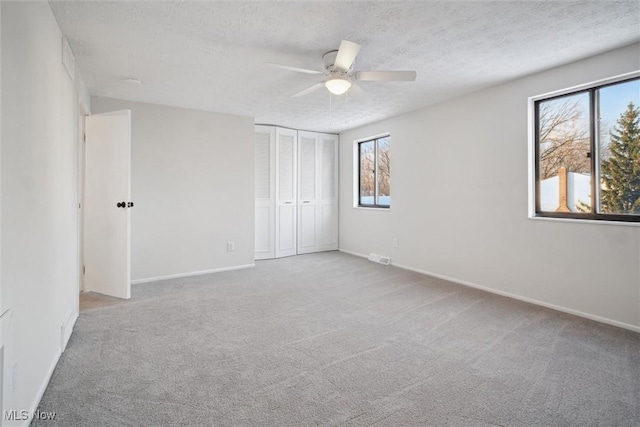 unfurnished bedroom with a textured ceiling, ceiling fan, a closet, and multiple windows