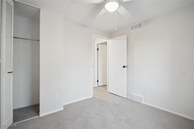 unfurnished bedroom featuring ceiling fan, a closet, and light carpet