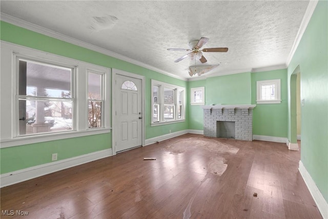 unfurnished living room with ceiling fan, a fireplace, wood-type flooring, a textured ceiling, and ornamental molding