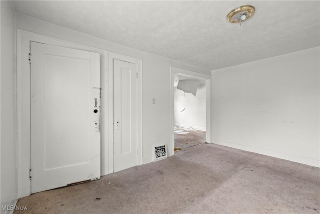 carpeted foyer featuring a textured ceiling