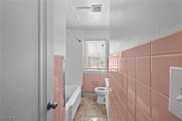 bathroom featuring toilet, tile walls, and shower / washtub combination