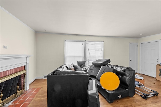 living room with a brick fireplace, crown molding, and light hardwood / wood-style flooring