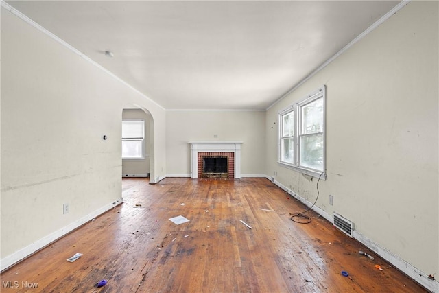 unfurnished living room featuring a brick fireplace, a baseboard radiator, wood-type flooring, and ornamental molding