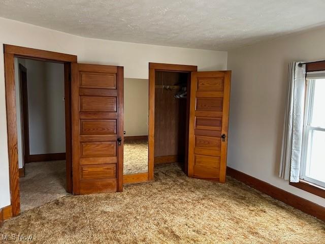 unfurnished bedroom with light colored carpet, a closet, and a textured ceiling