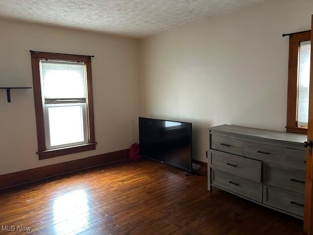 unfurnished bedroom with dark hardwood / wood-style flooring and a textured ceiling