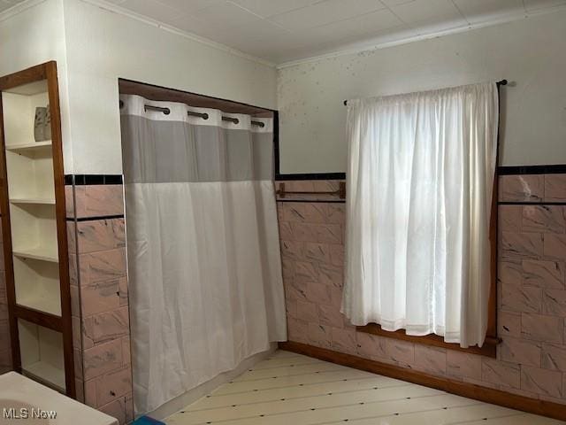 bathroom with tile walls, hardwood / wood-style floors, and crown molding