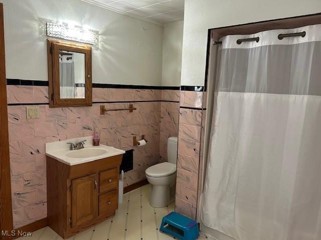 bathroom featuring walk in shower, vanity, toilet, and tile walls