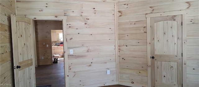 hall with dark hardwood / wood-style flooring and wooden walls