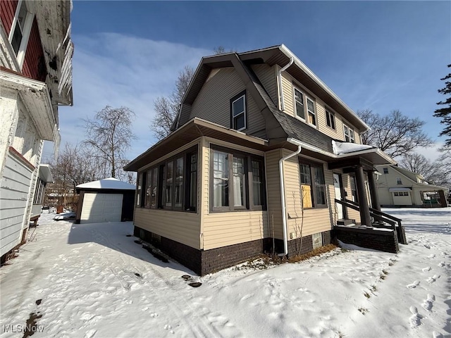 view of snowy exterior with a garage and an outbuilding