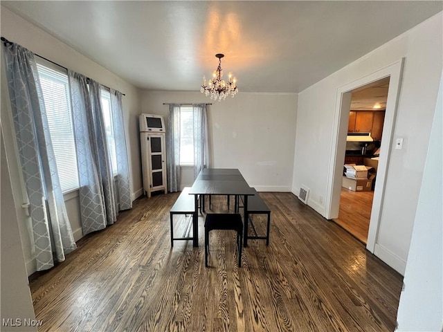 dining space with dark hardwood / wood-style flooring and a chandelier