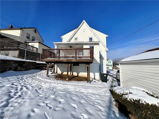 snow covered back of property with a wooden deck