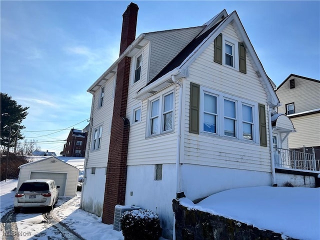 view of snow covered exterior featuring a garage and an outdoor structure