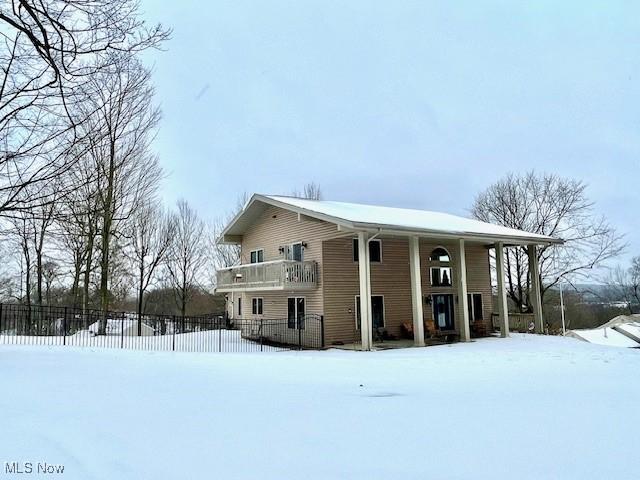 snow covered back of property with a balcony