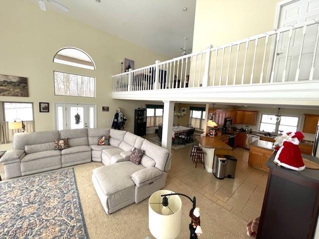 living room featuring a high ceiling, ceiling fan, and light tile patterned flooring