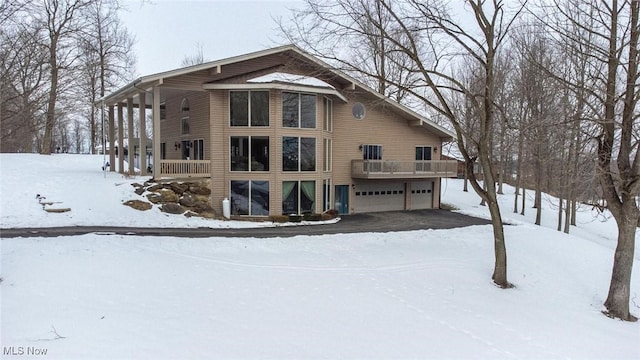 snow covered house featuring a garage