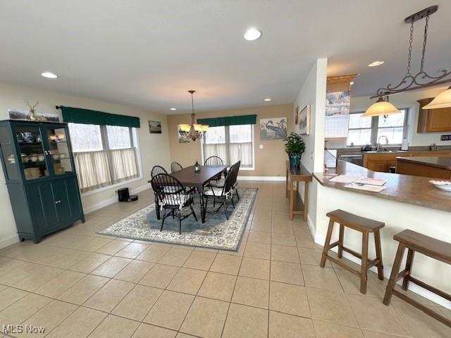 tiled dining room featuring sink, a notable chandelier, and plenty of natural light