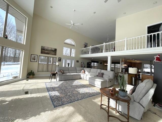 carpeted living room with a high ceiling, a healthy amount of sunlight, and ceiling fan