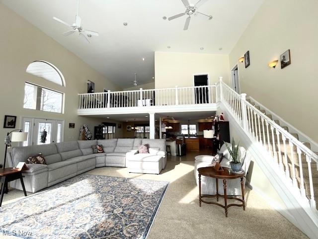 carpeted living room featuring ceiling fan and a towering ceiling