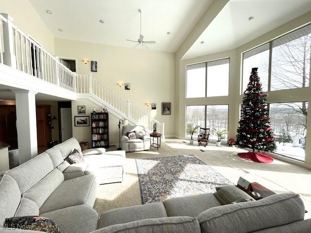 living room with carpet, ceiling fan, and a high ceiling