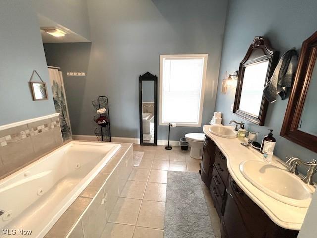 bathroom featuring a relaxing tiled tub, tile patterned floors, toilet, and vanity