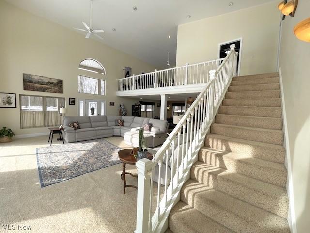 carpeted living room featuring a towering ceiling and ceiling fan