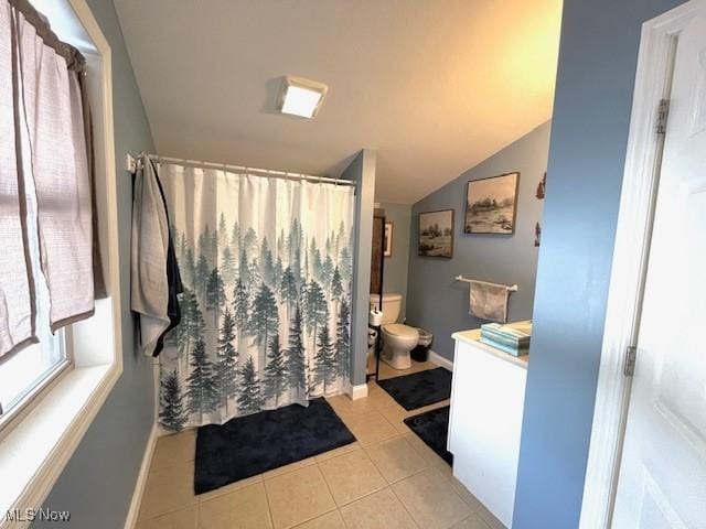 bathroom with lofted ceiling, tile patterned flooring, vanity, toilet, and a shower with curtain