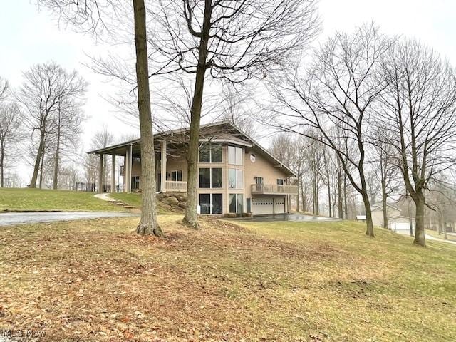 rear view of property featuring a garage and a lawn