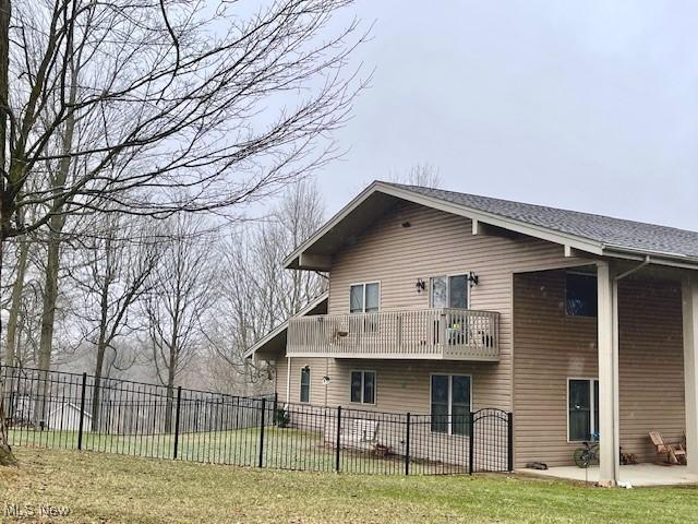 rear view of property with a balcony, a yard, and a patio area