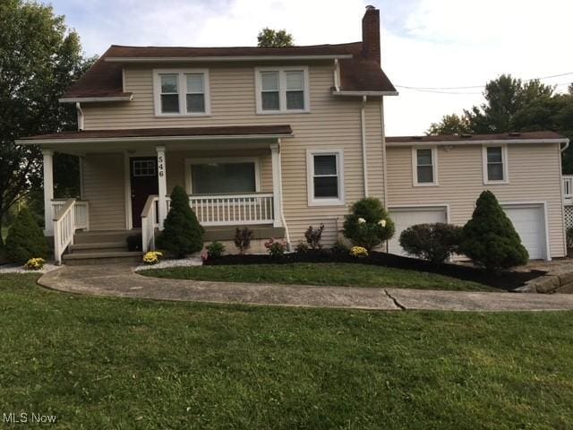 view of front of home featuring a front lawn, covered porch, and a garage