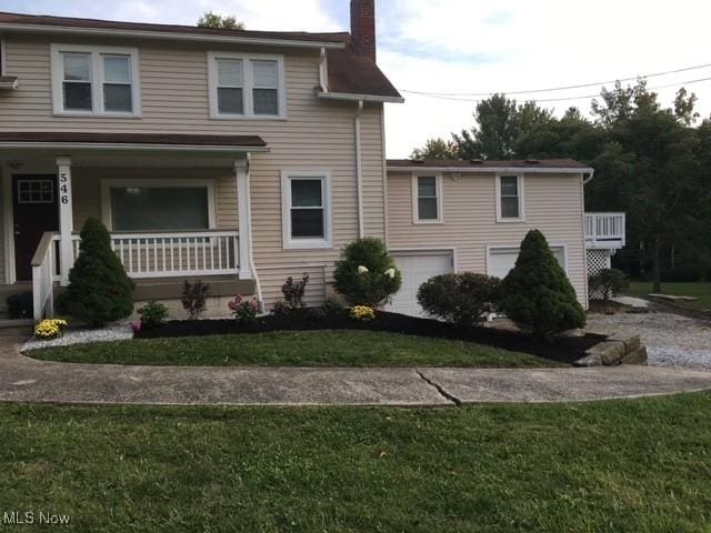 view of front facade featuring a garage, a front yard, and a porch