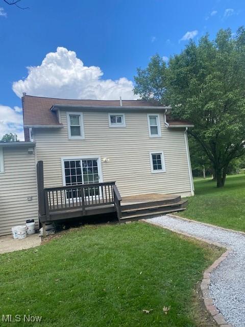 back of house featuring a lawn and a wooden deck