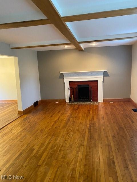 unfurnished living room featuring coffered ceiling, beam ceiling, and wood-type flooring