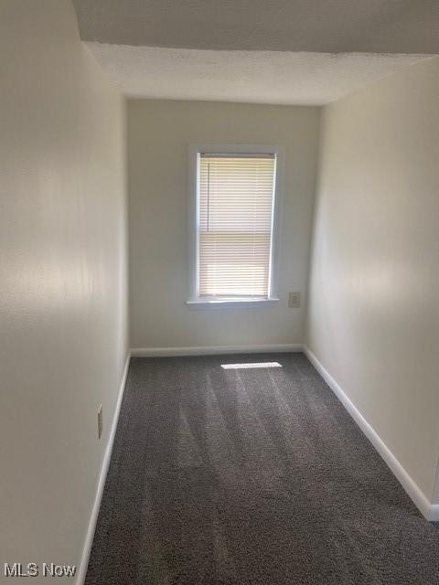 unfurnished room featuring dark carpet