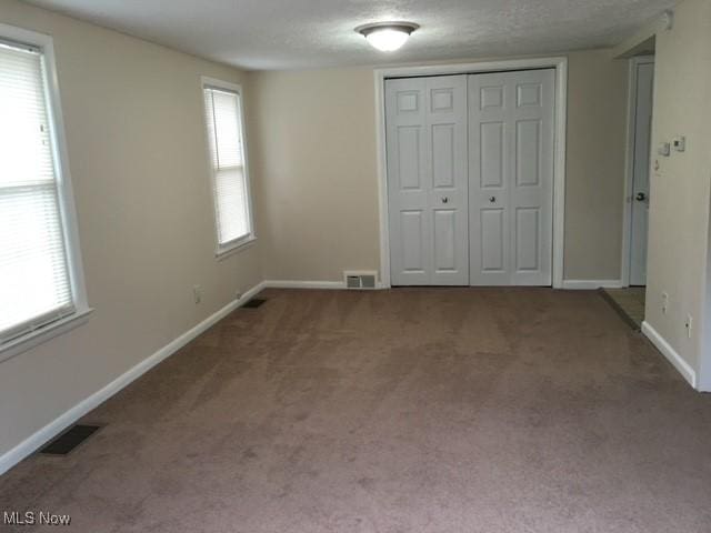 unfurnished bedroom featuring a textured ceiling, a closet, and carpet flooring