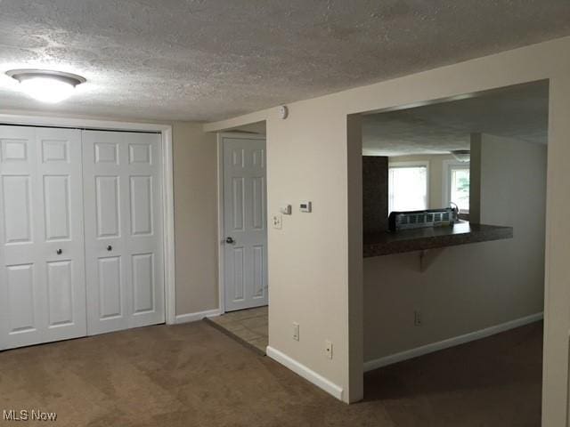 interior space with dark carpet and a textured ceiling