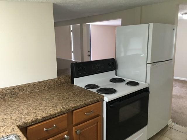 kitchen featuring light tile patterned floors, range with electric stovetop, and stone counters