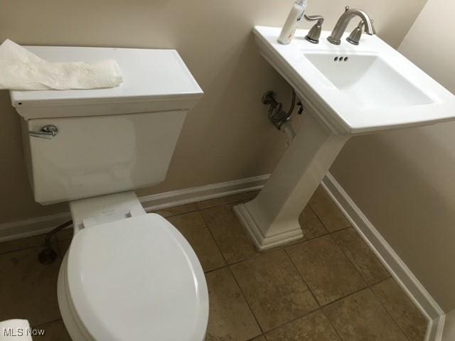 bathroom with toilet, tile patterned flooring, and sink