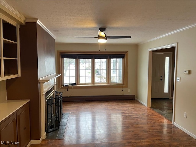 unfurnished living room with ceiling fan, dark hardwood / wood-style floors, a fireplace, crown molding, and baseboard heating