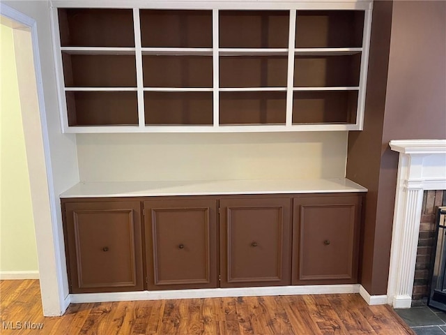 room details featuring hardwood / wood-style floors, a tiled fireplace, and built in shelves