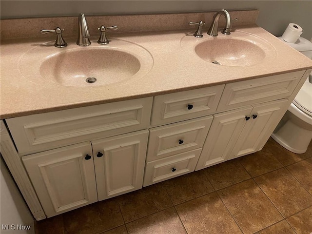 bathroom with toilet, vanity, and tile patterned floors