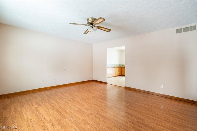 empty room with ceiling fan, a textured ceiling, and light hardwood / wood-style flooring