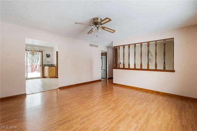 unfurnished room with a textured ceiling, ceiling fan with notable chandelier, and light hardwood / wood-style flooring