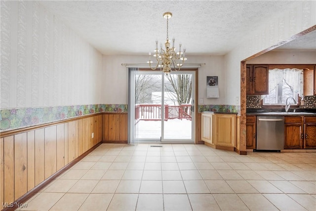 kitchen featuring a textured ceiling, sink, hanging light fixtures, a chandelier, and stainless steel dishwasher