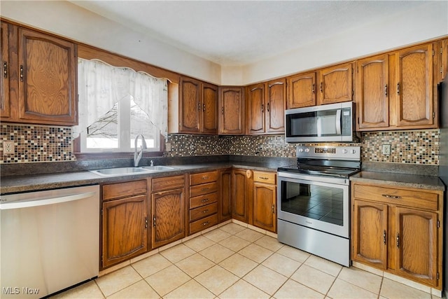 kitchen with light tile patterned flooring, stainless steel appliances, decorative backsplash, and sink